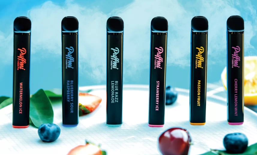 puffmi tx600 pro new vape disposable range - 6 pen sized black disposable ecigarettes sit infront of a blue background surrounded by fruit
