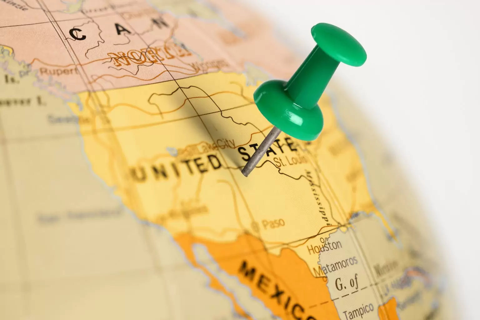 Green pin on a globe pointing to the united states