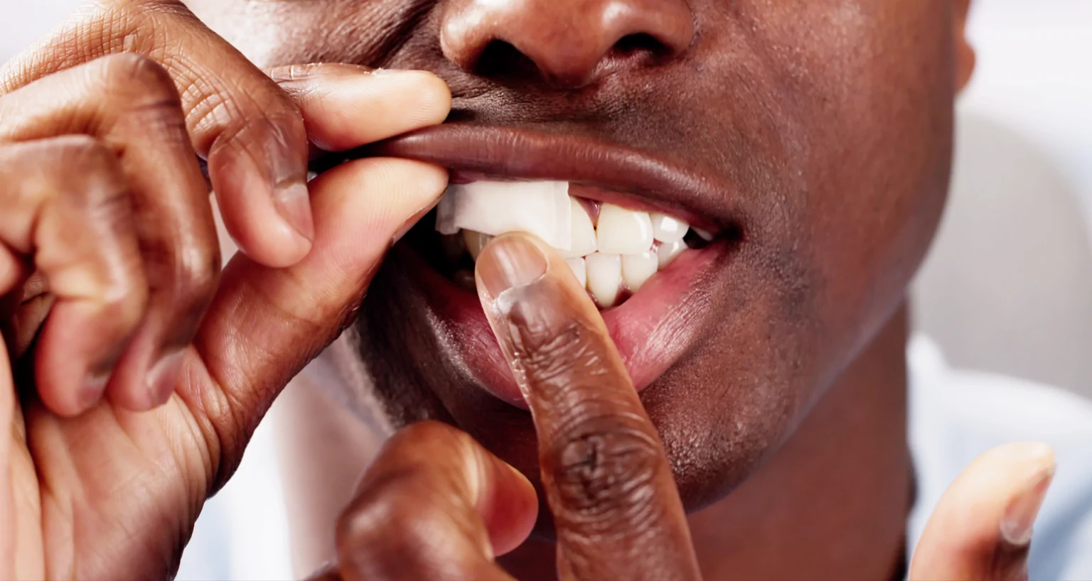 man placing white nicotine pouch under his gum